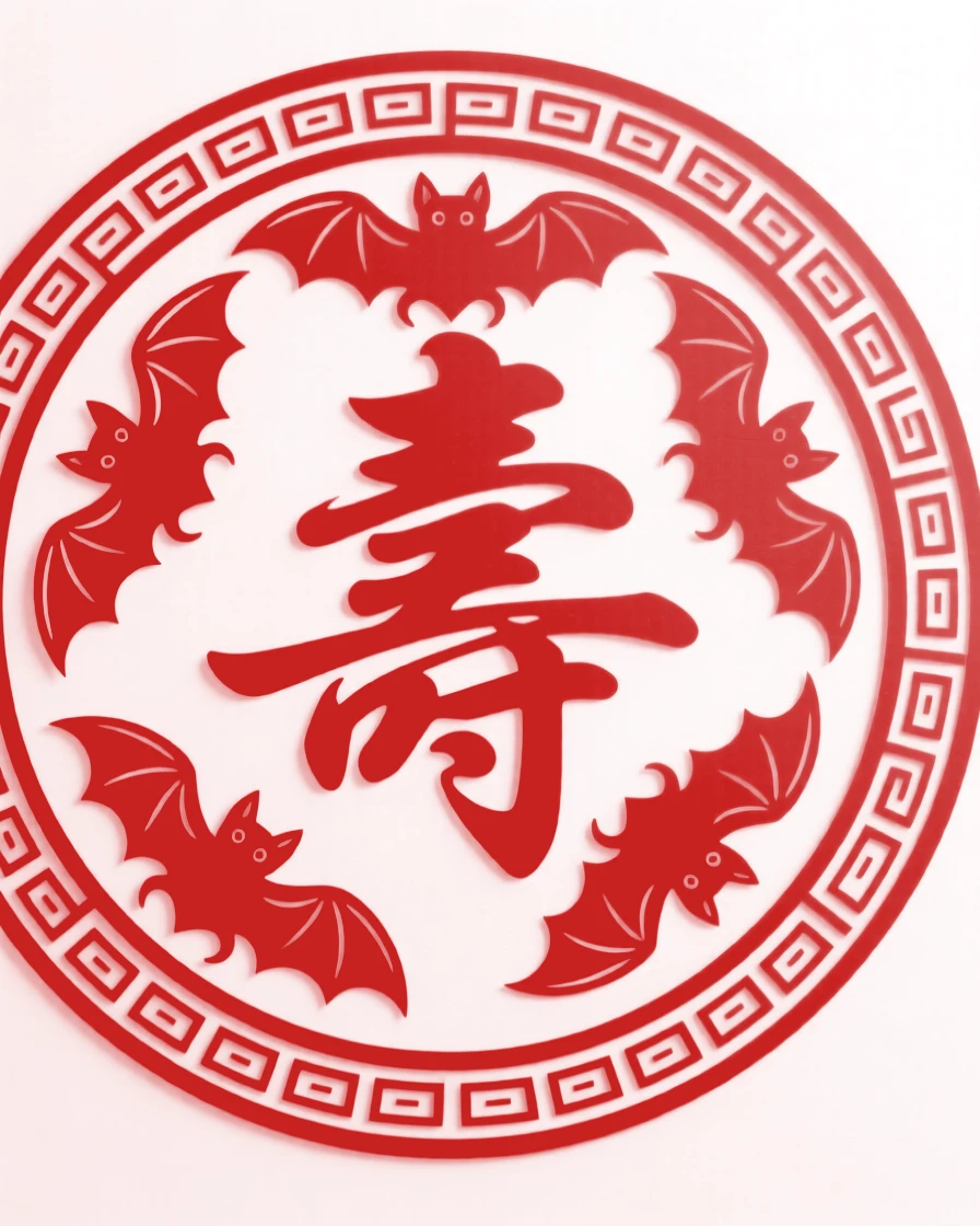 A design of a circular medallion featuring a ring of five bats around a longevity character, bordered by a fine repeating key-fret pattern.