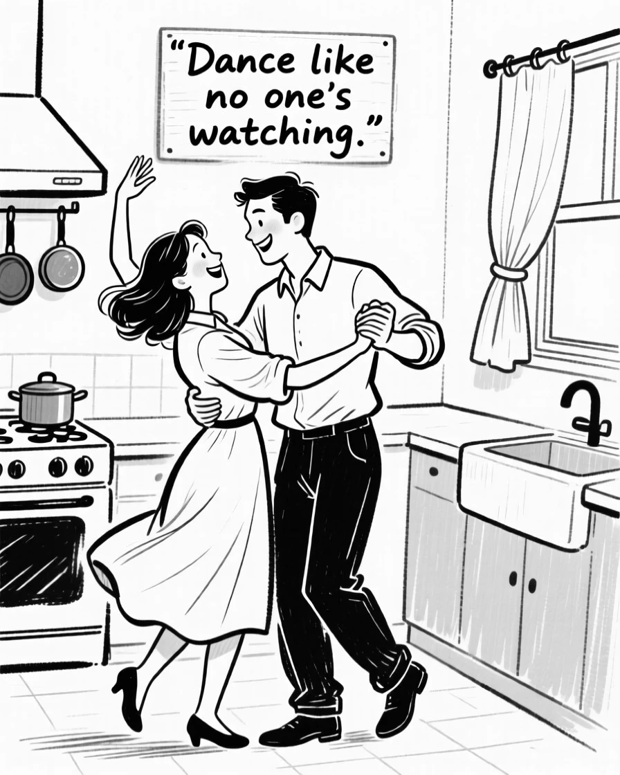 A couple dancing together in their kitchen, one hand raised, both smiling.