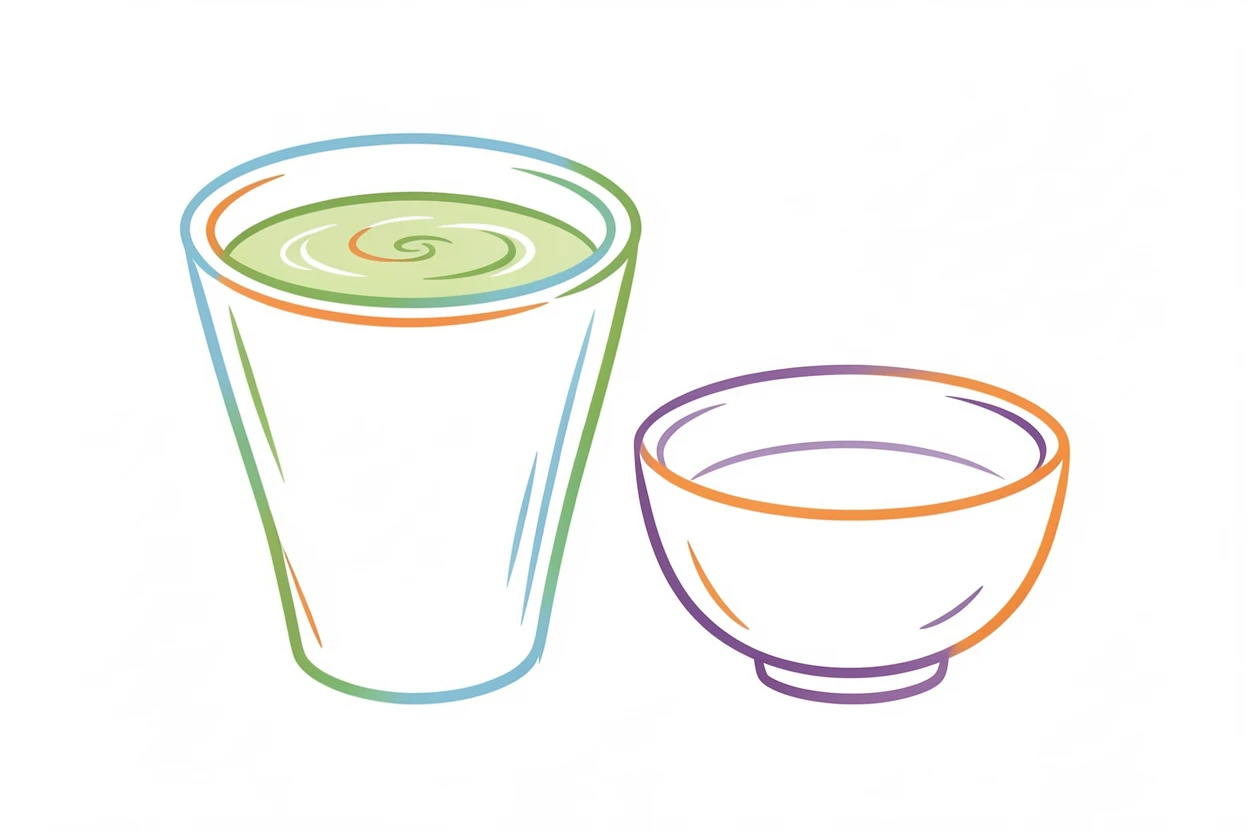 A cup of matcha tea whisked to a frothy green beside a small ceramic bowl.