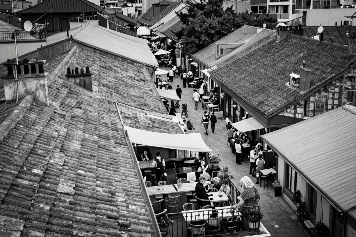 A rooftop café overlooks a maze of old rooftops beside a bustling plaza.