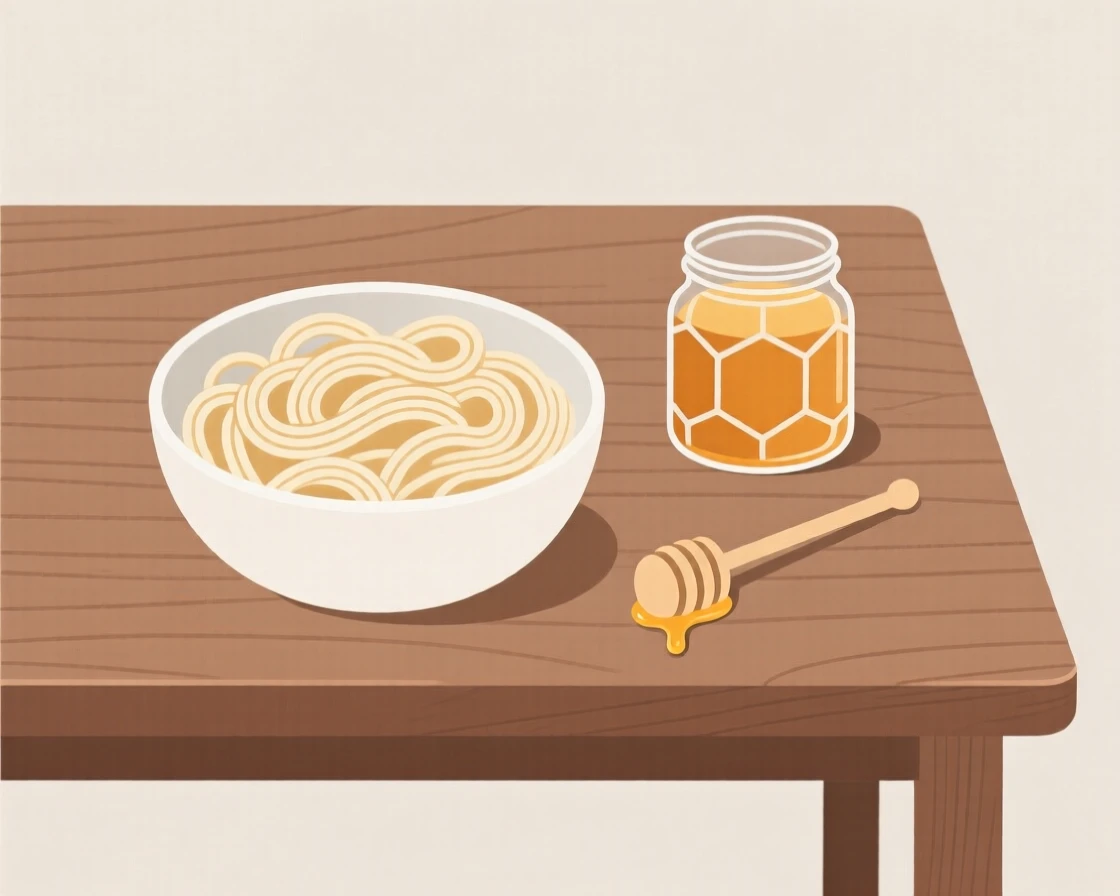 A homemade bowl of creamy pasta cooling near a glass jar of honey on a rustic wooden table, expressing fresh vibrance.