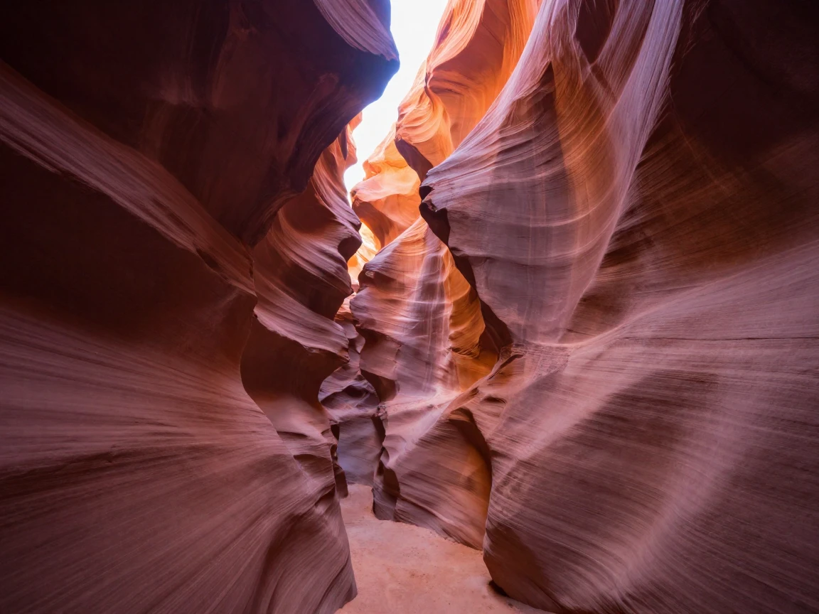 A narrow canyon slot glows orange and pink as light filters down from a crack far above.